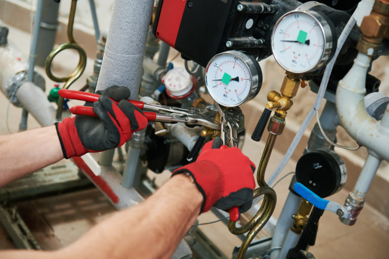 heating equipment inspecting. engineer or plumber in boiler room screwing or adjusting manometer